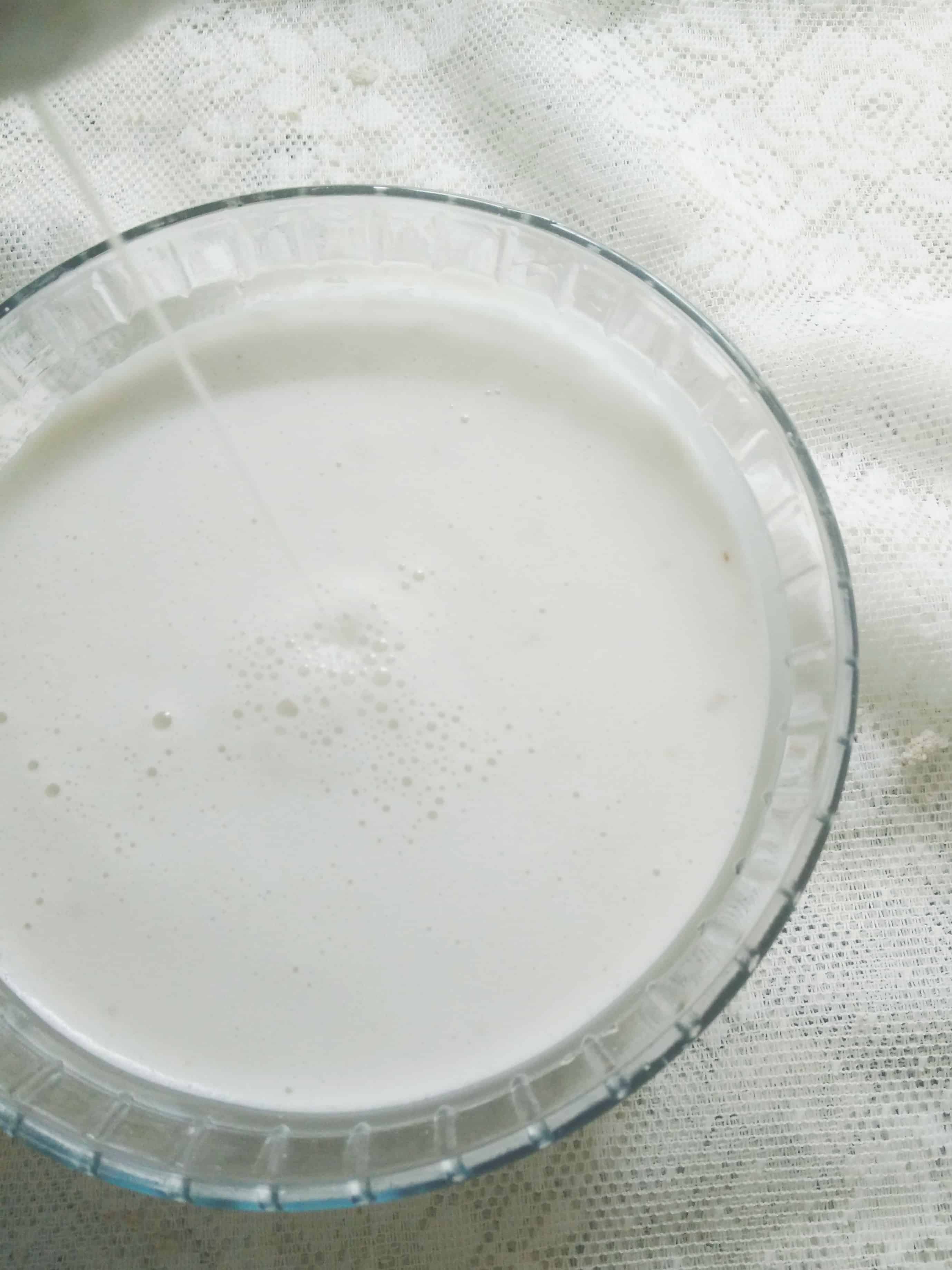 Almond milk getting strained in a glass bowl.