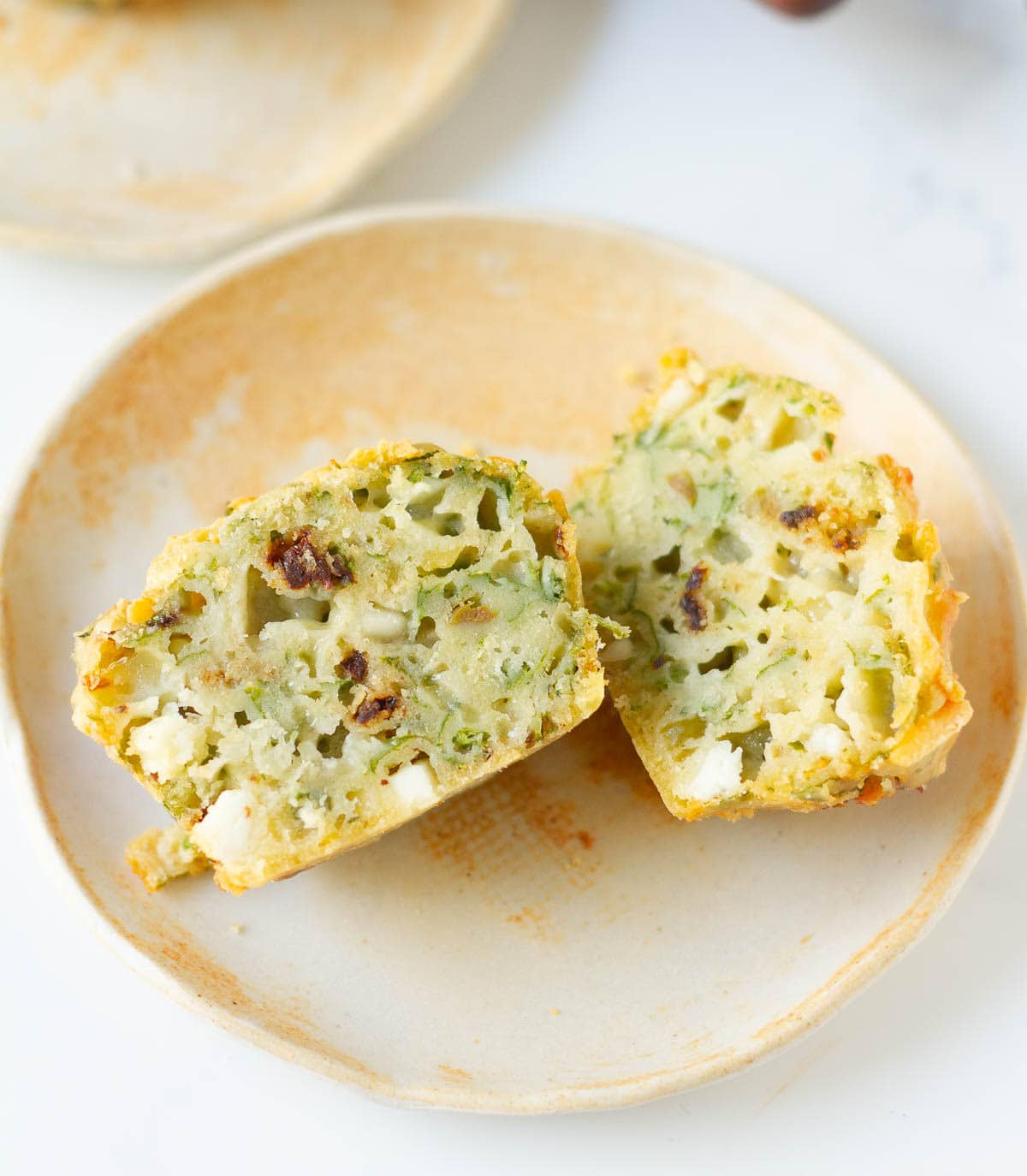 A feta spinach muffin cut into half on a small plate.