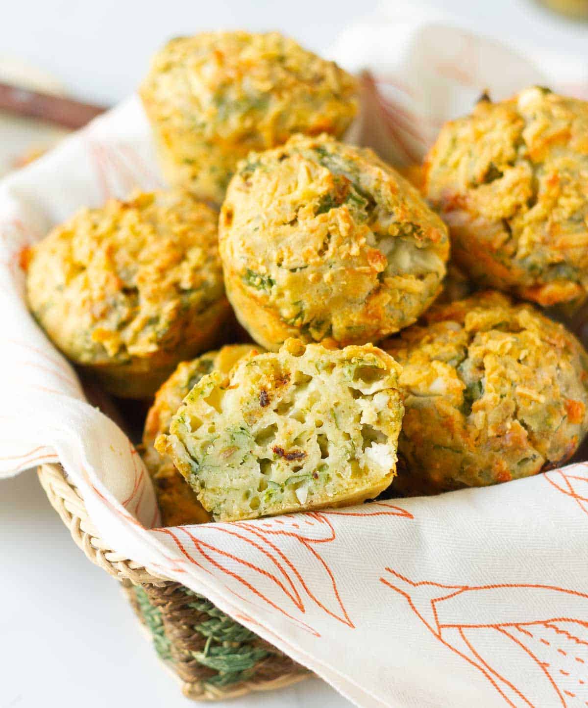 A basket of spinach muffins with one muffin cut in half.