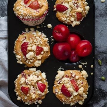 Plum & Cardamom Muffins in a muffin tray with plums.