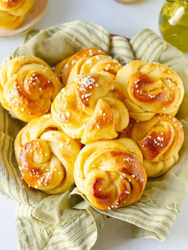 orange brioche sweet rolls piled up on a green napkin.