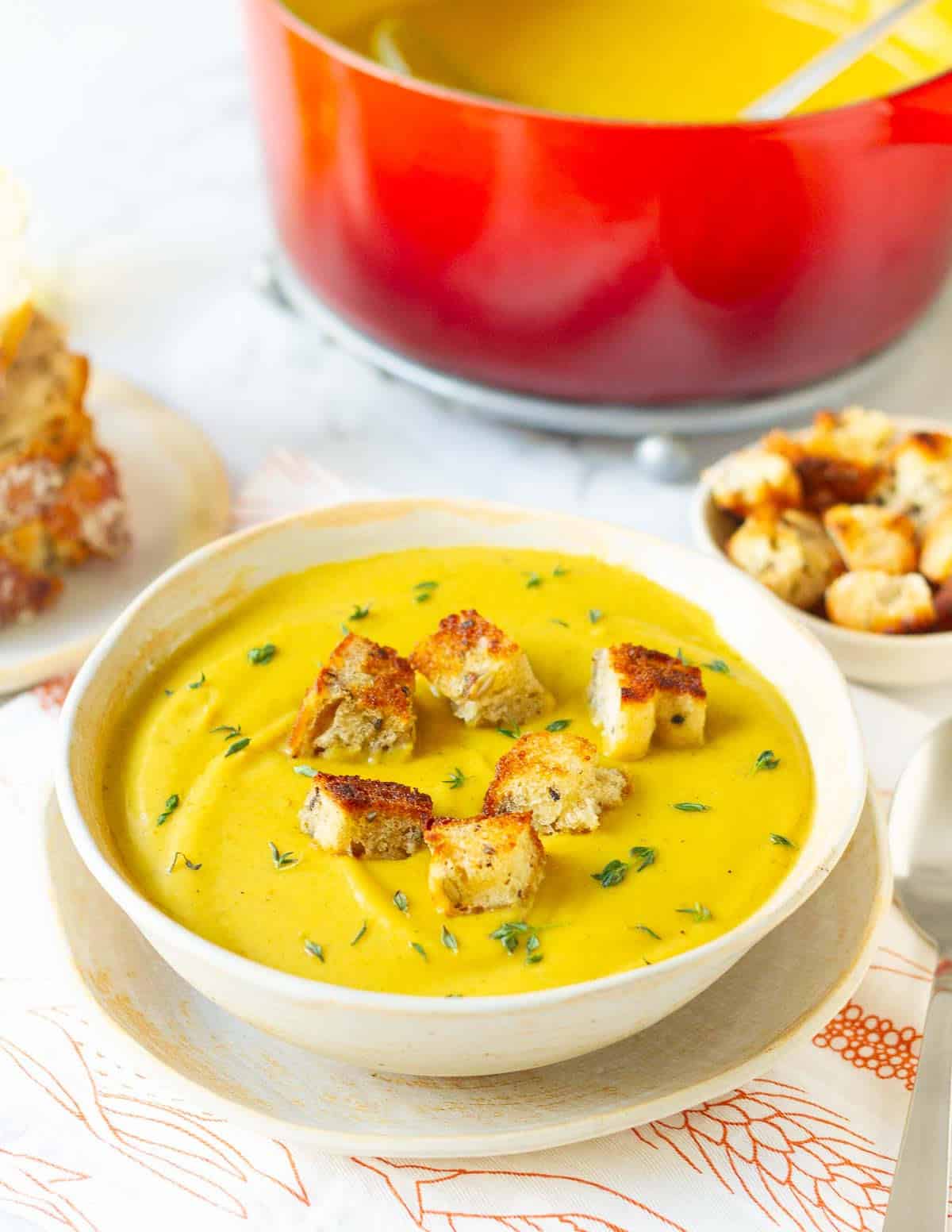 sweet potato soup in a bowl garnished with croutons and fresh thyme.