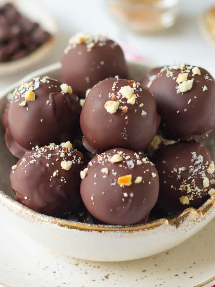 peanut chocolate protein balls topped with peanuts and seasalt in a small bowl.