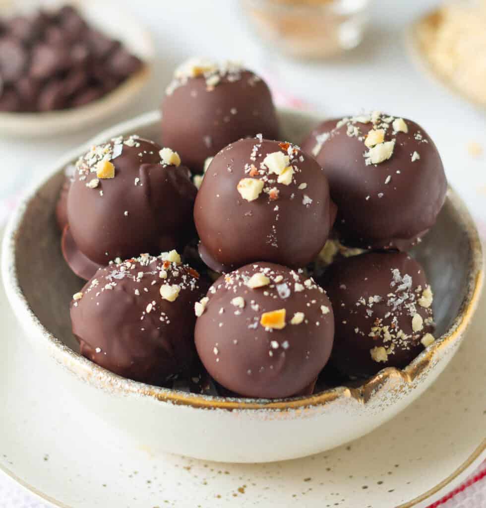 peanut chocolate protein balls topped with peanuts and seasalt in a small bowl.