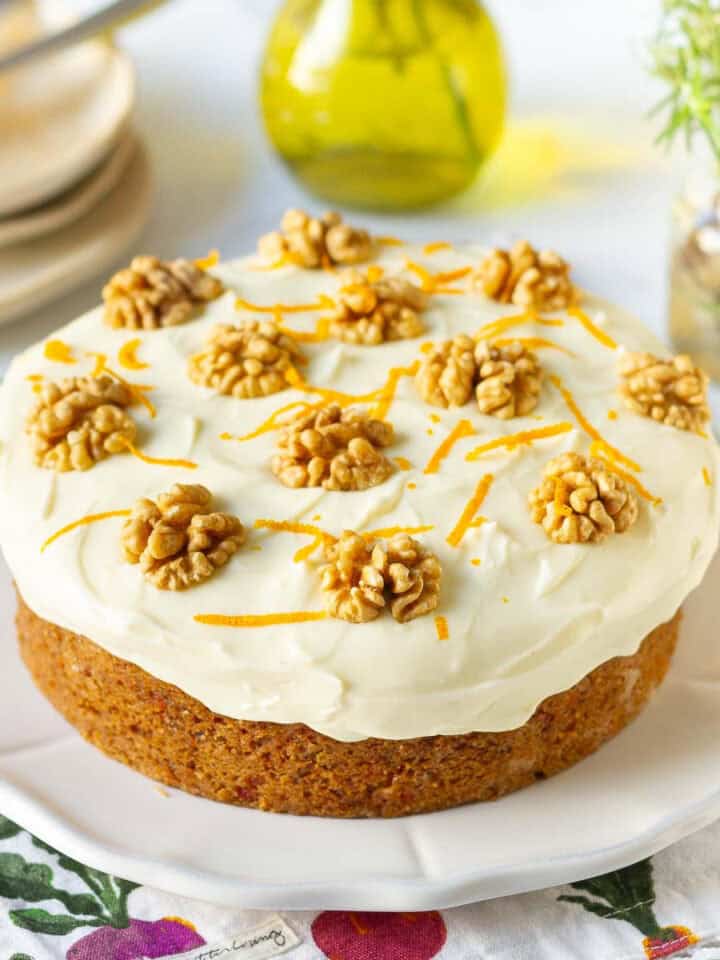Eggless carrot cake with cream cheese frosting on a white platter.