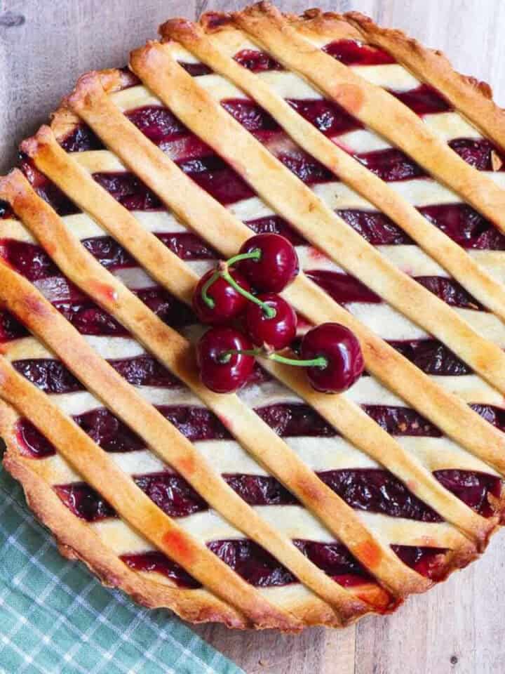 Cherry pie with a few fresh cherries on top.