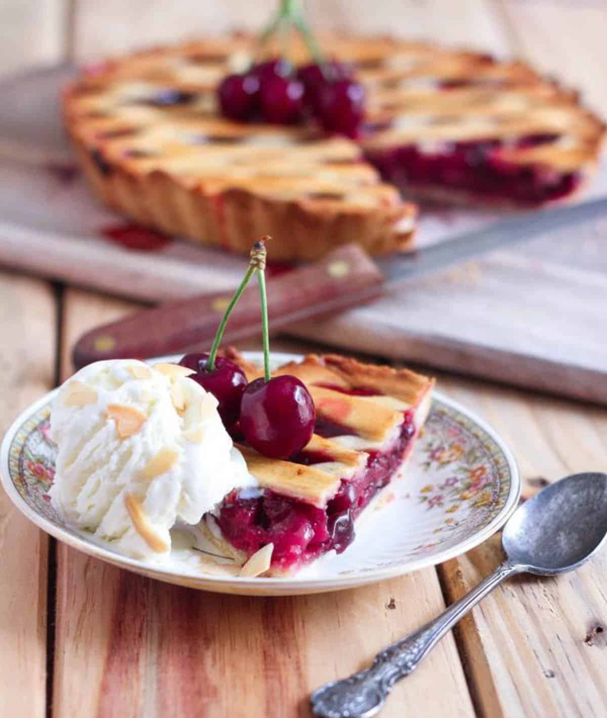 A slice of cherry pie with a scoop of vanilla ice cream.