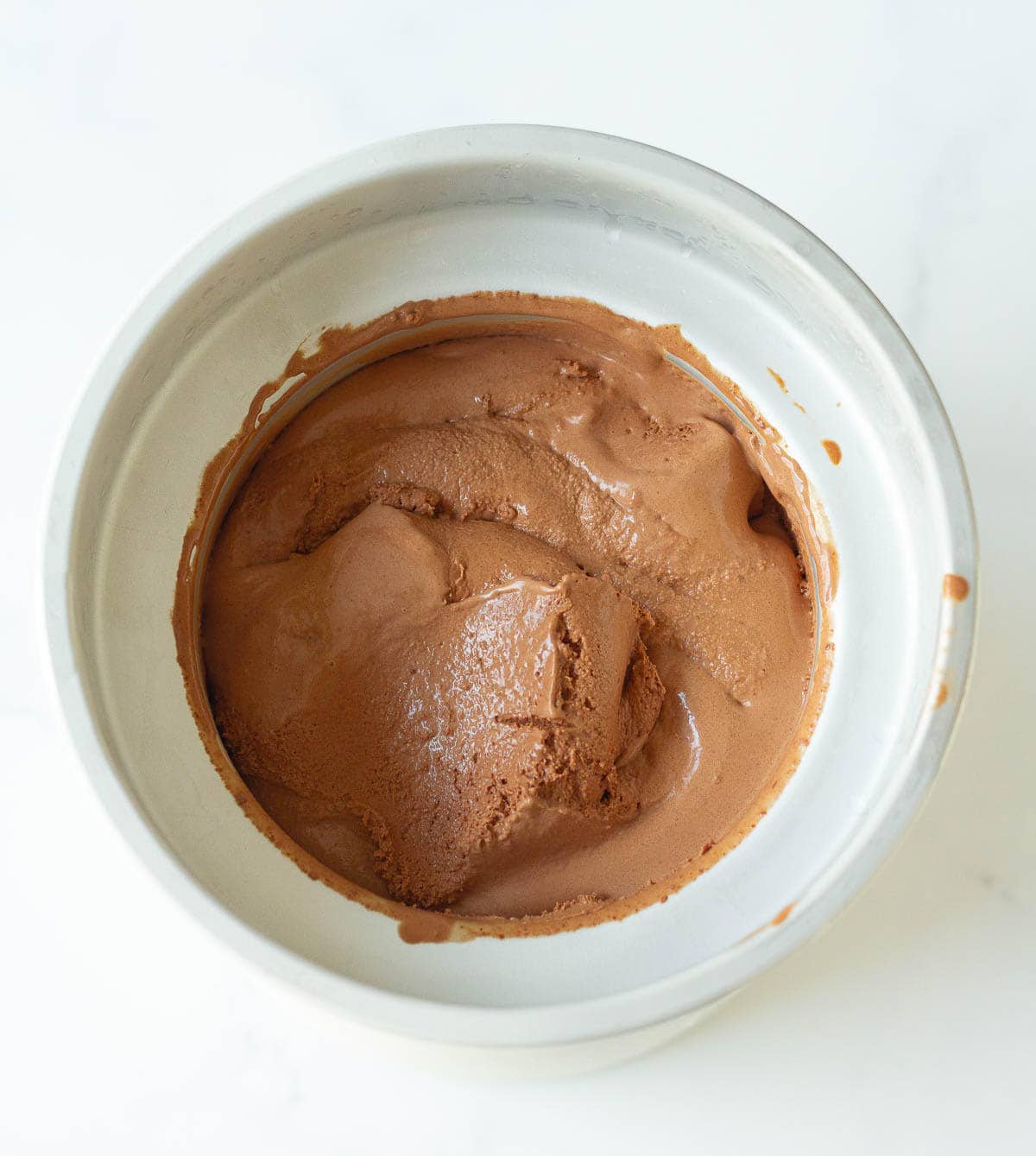 Churned chocolate almond ice cream in ice cream maker bowl.