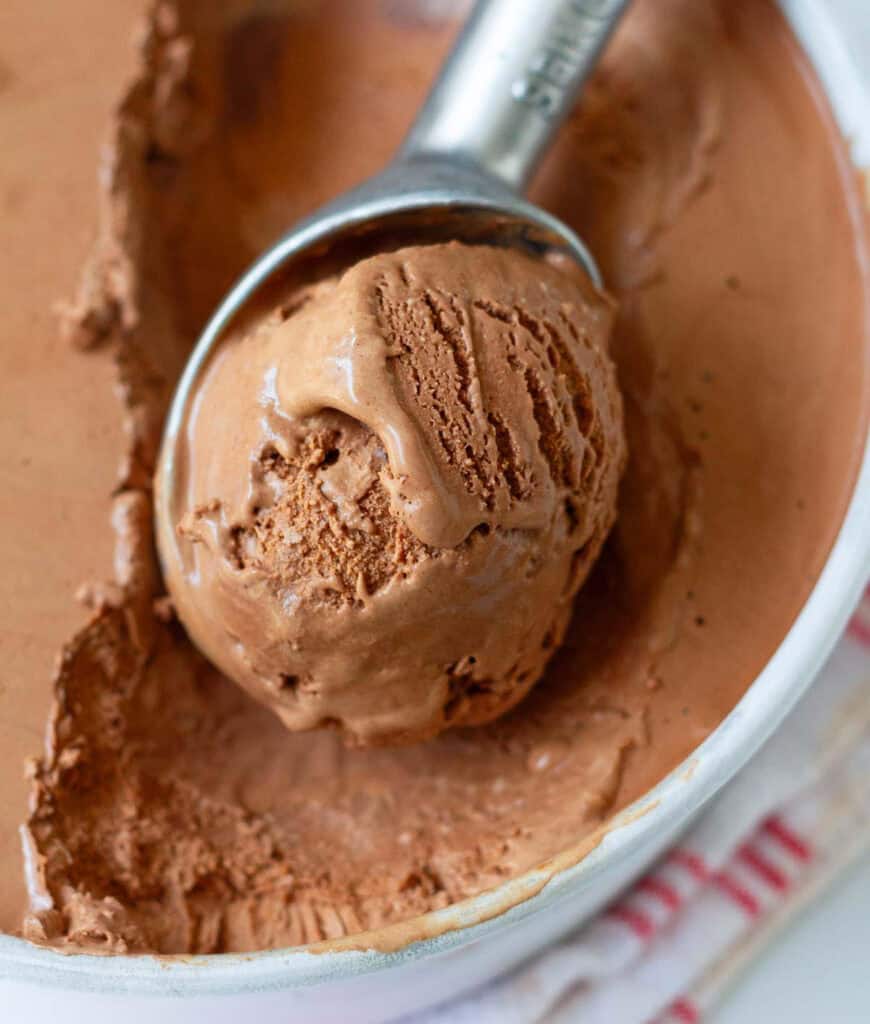 A scoop of chocolate ice cream in an ice cream tub.