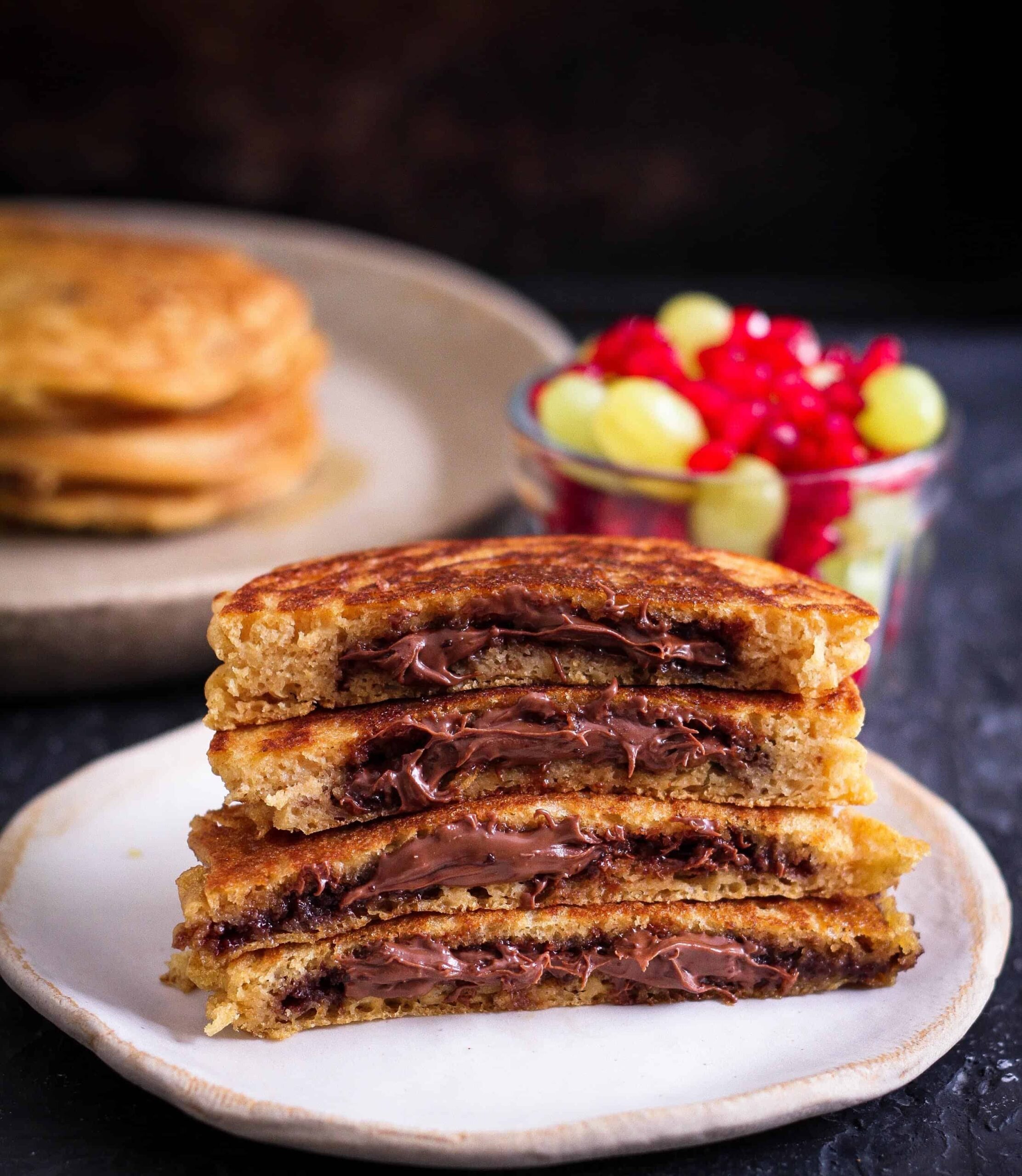 halves of chocolate stuffed pancakes stacked on a plate.