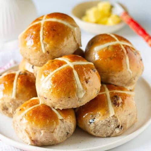 Hot cross buns stacked up on a plate.