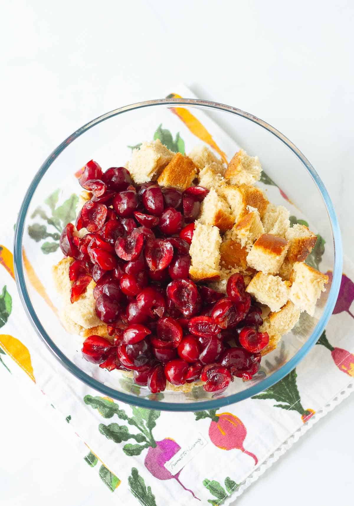 Bread cubes and pitted cherries in a large bowl.