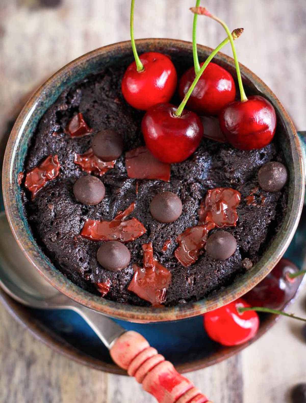 Chocolate cherry mug cake with fresh cherries on top.