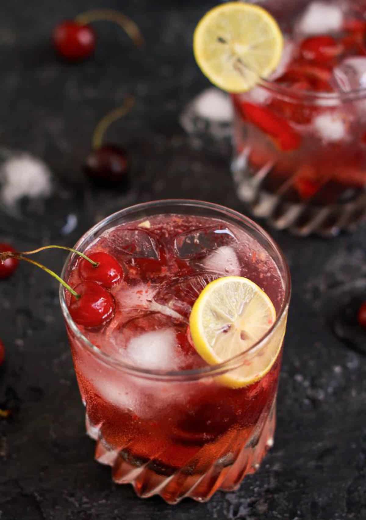 2 glasses of cherry gin cocktail with fresh cherries.