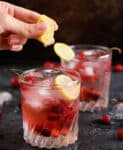 a hand squeezing lemon juice into a glass of gin and tonic.