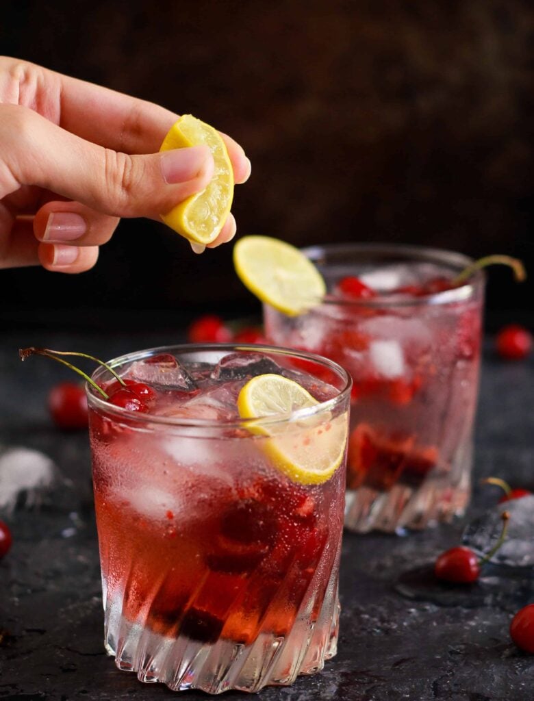 Cherry Gin And Tonic refreshing summer cocktail with a squeeze of lemon juice