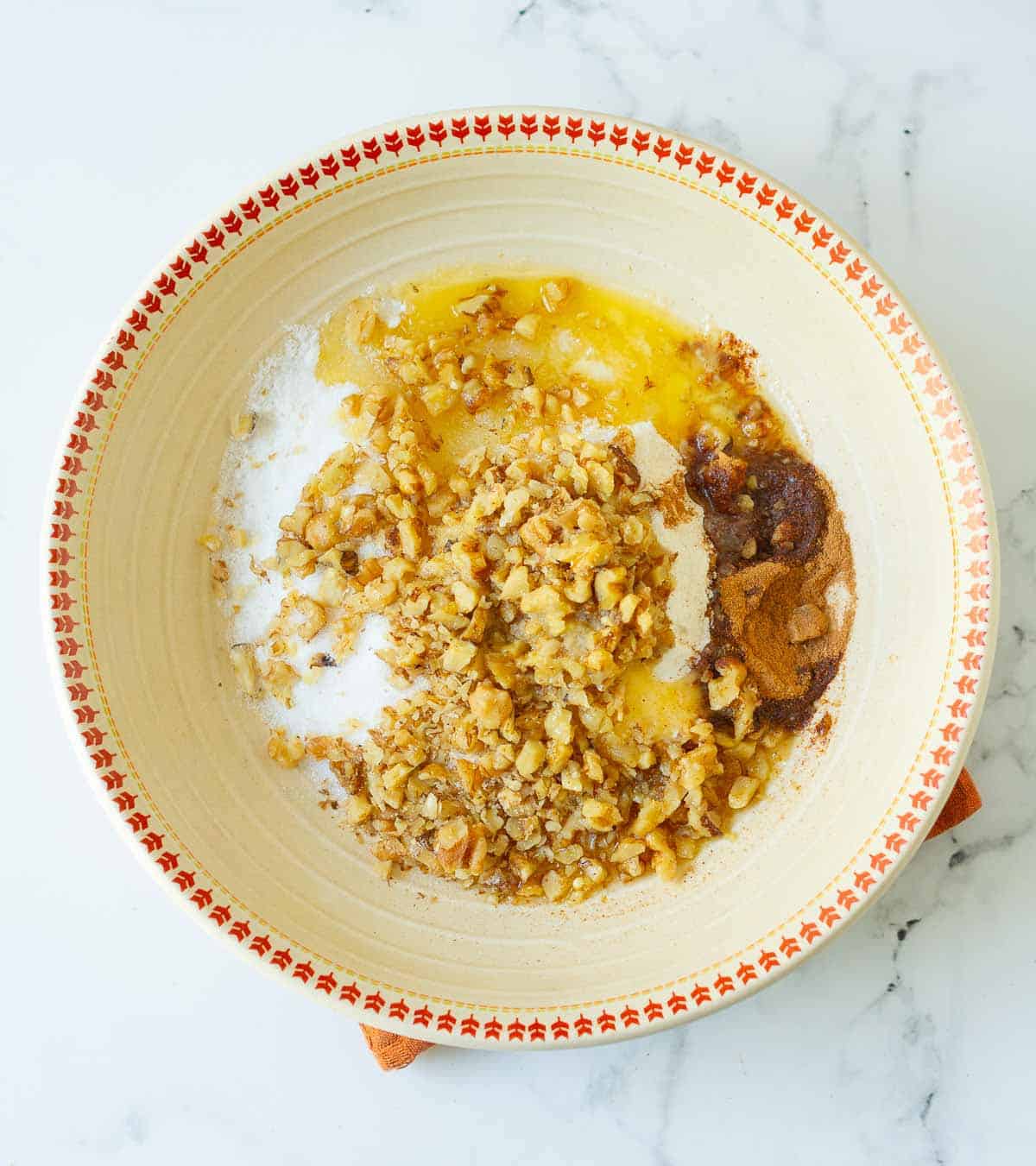 Melted butter, flour, walnuts, sugar, and cinnamon powder in a bowl.