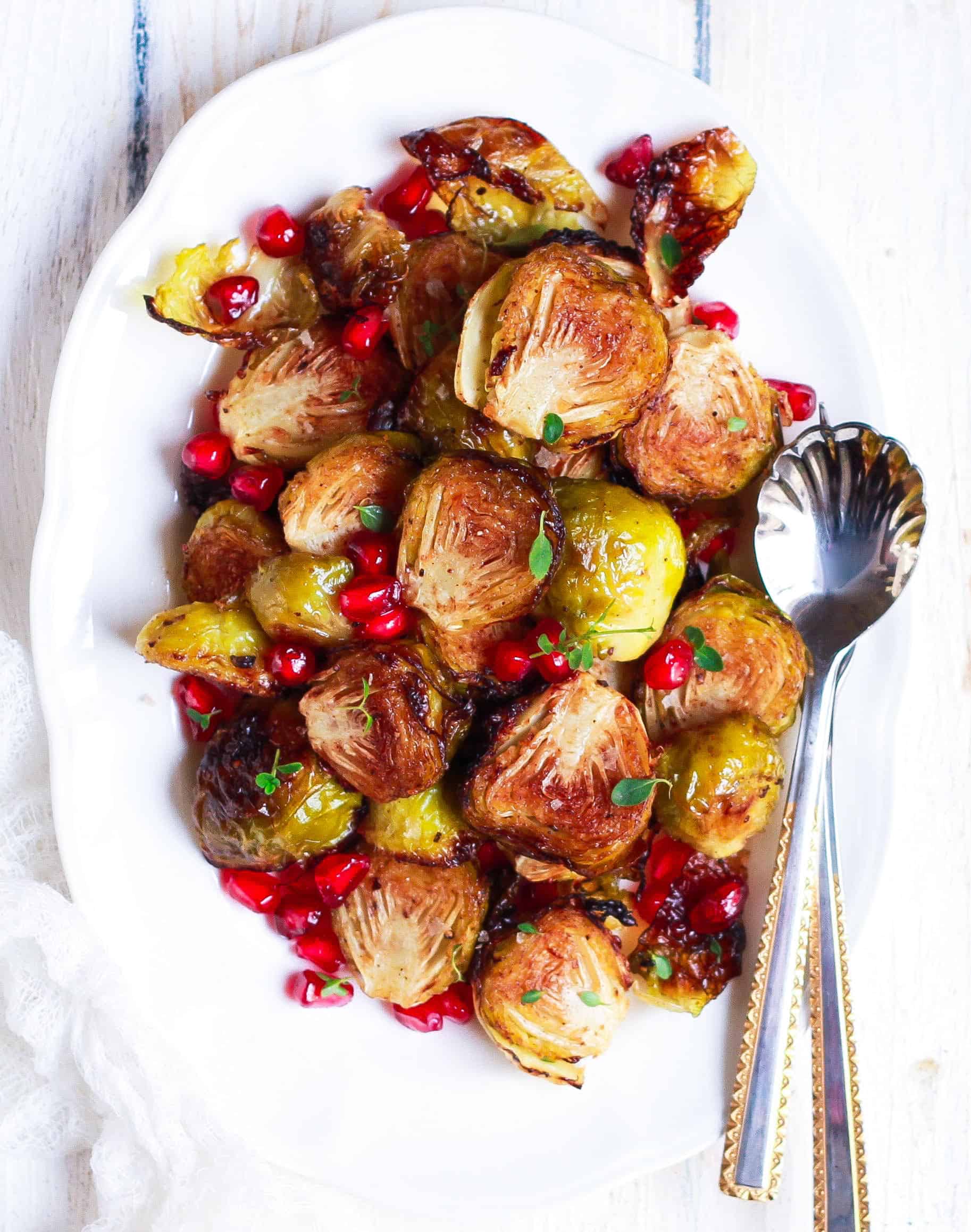 roasted brussels sprouts on a white platter with spoon.
