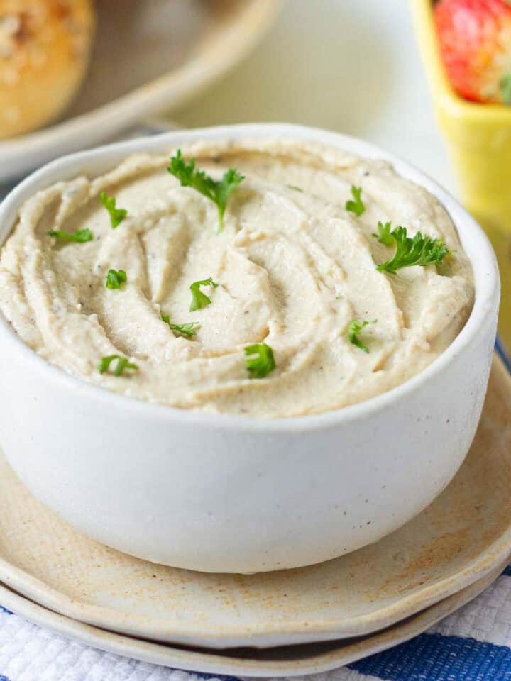 cashew ricotta cheese garnished with parsley in a small bowl place on 2 plates.