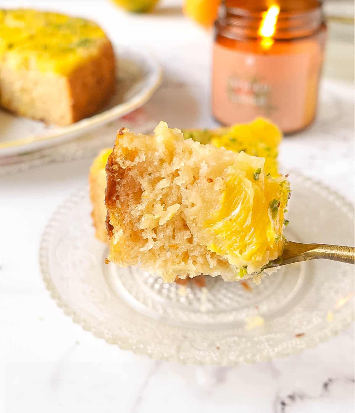 A bite of cake with oranges on a fork.