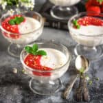 coconut panna cotta in glass bowls with strawberry sauce on top.