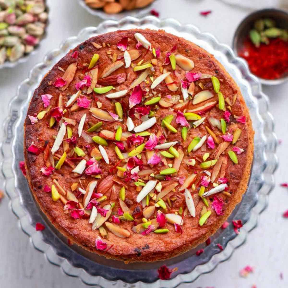 Mawa cake with almonds and pistachios on a cake platter.