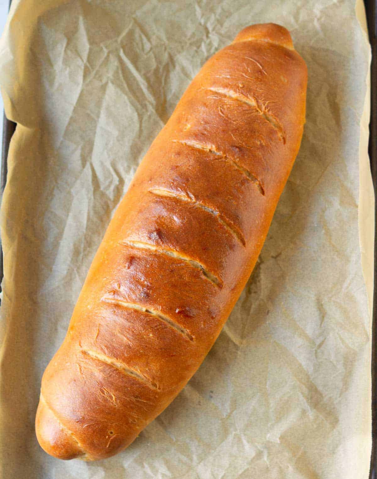 Baked loaf of bread on parchment paper.