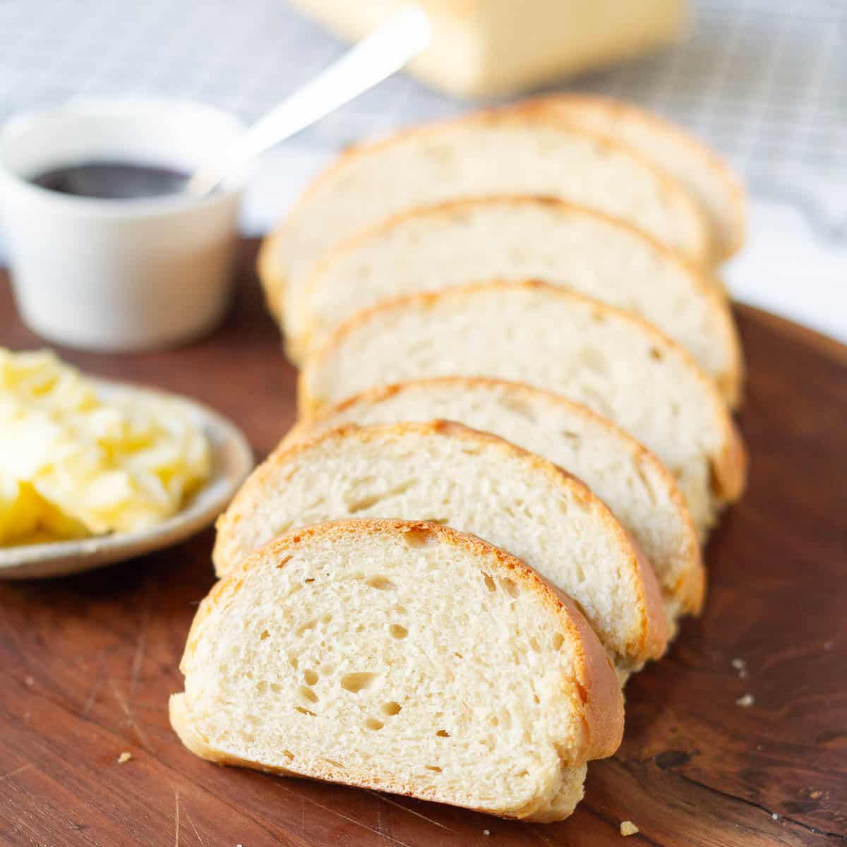 Sliced bread with butter and jam on a wooden board.