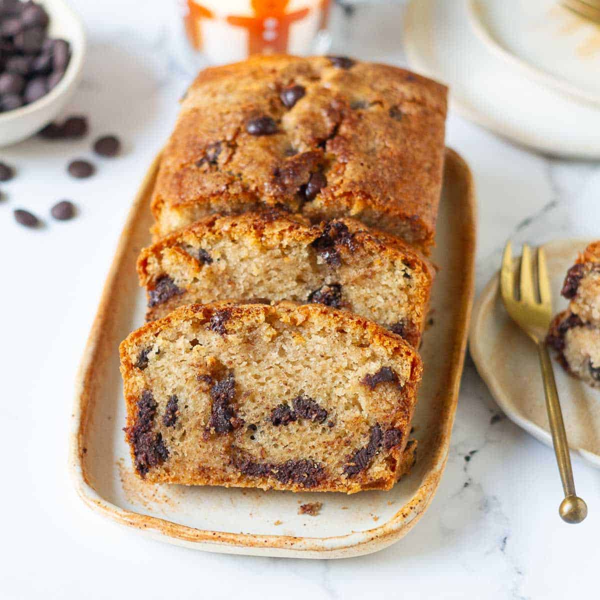 Sliced chocolate chip cake on a platter with ingredients in the background.