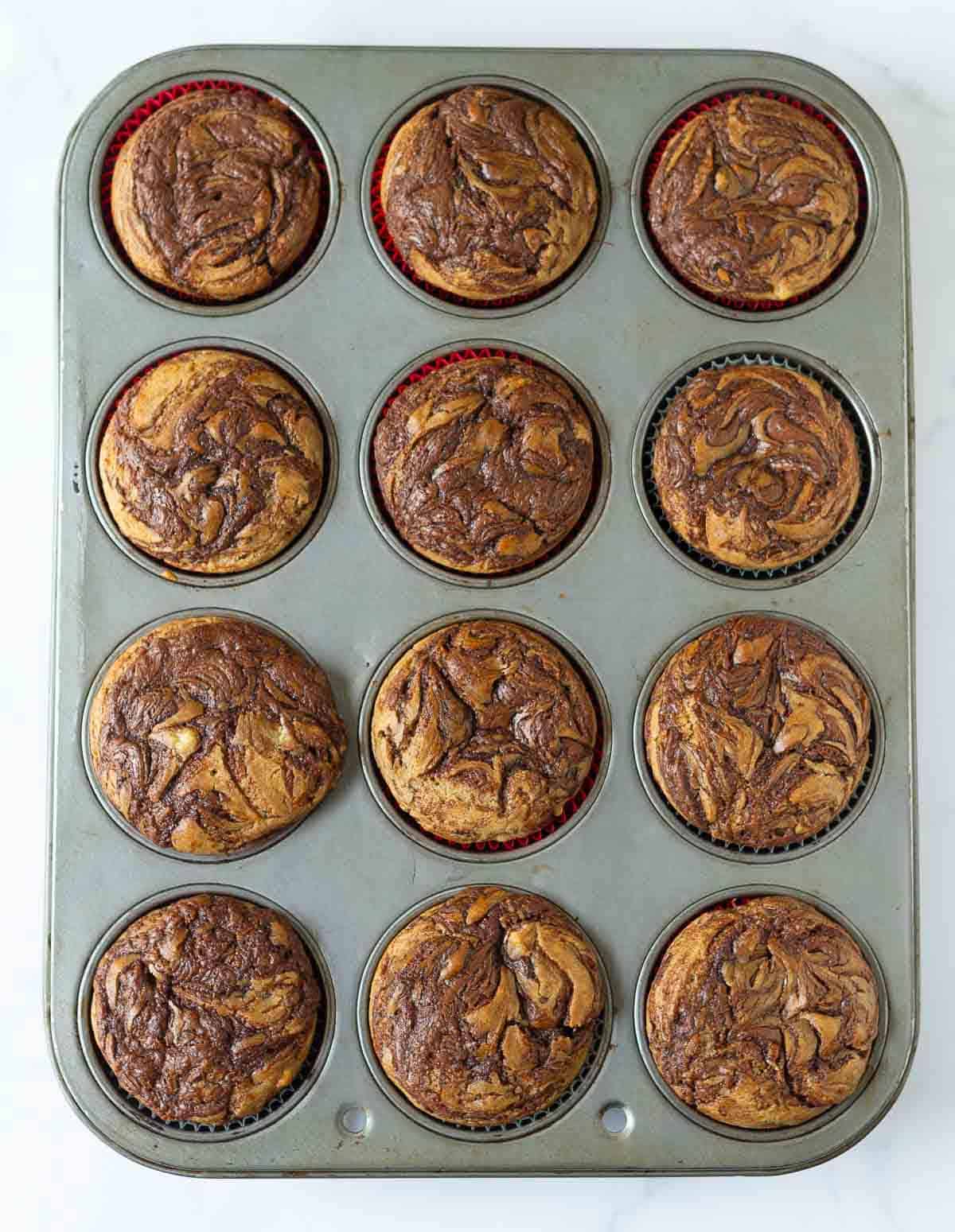 Baked Nutella banana muffins in a muffin tray.