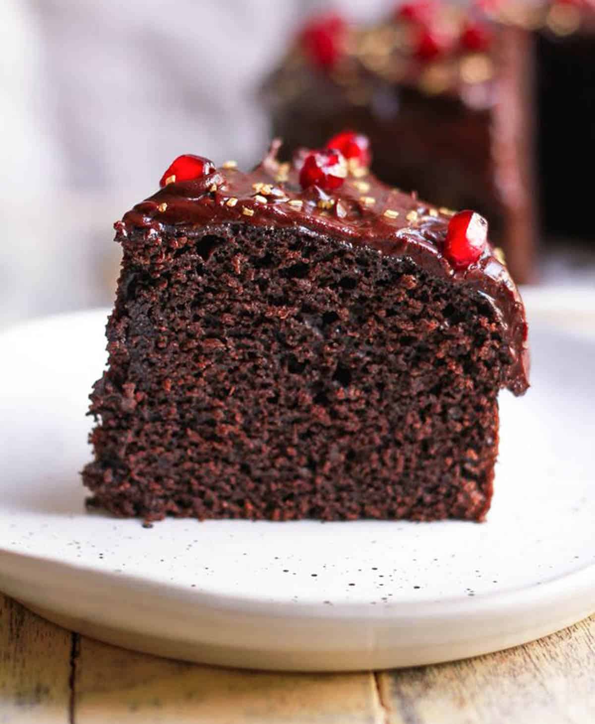 A slice of chocolate cake with ganache on a small plate.