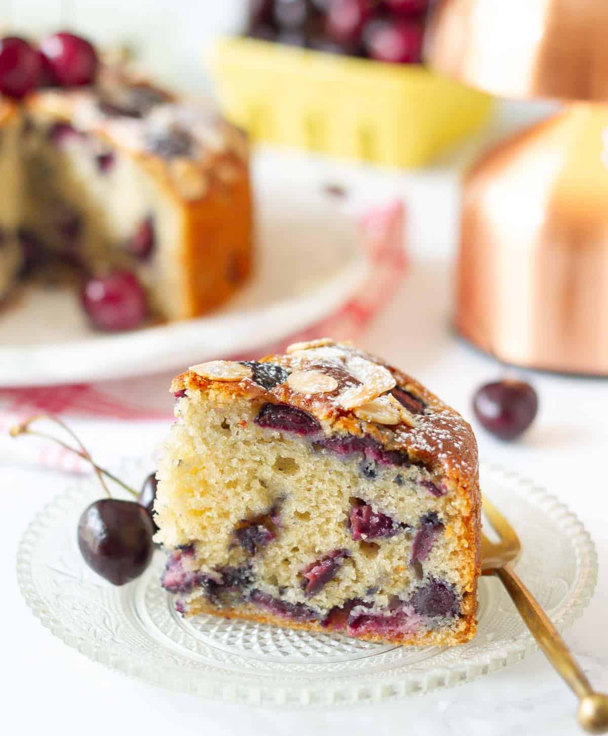 A slice of cherry cake on a small plate with a fork.