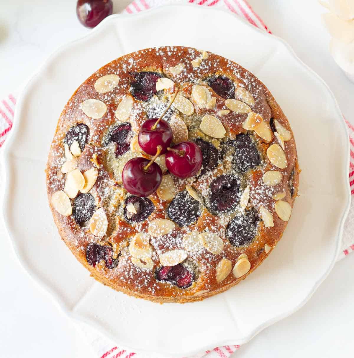 Cake with fresh cherries and almonds on a plate.