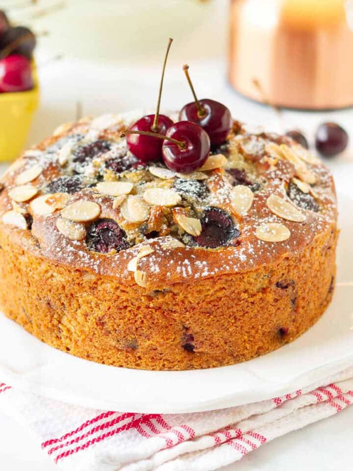 Fresh cherry cake with cherries on top on a platter.