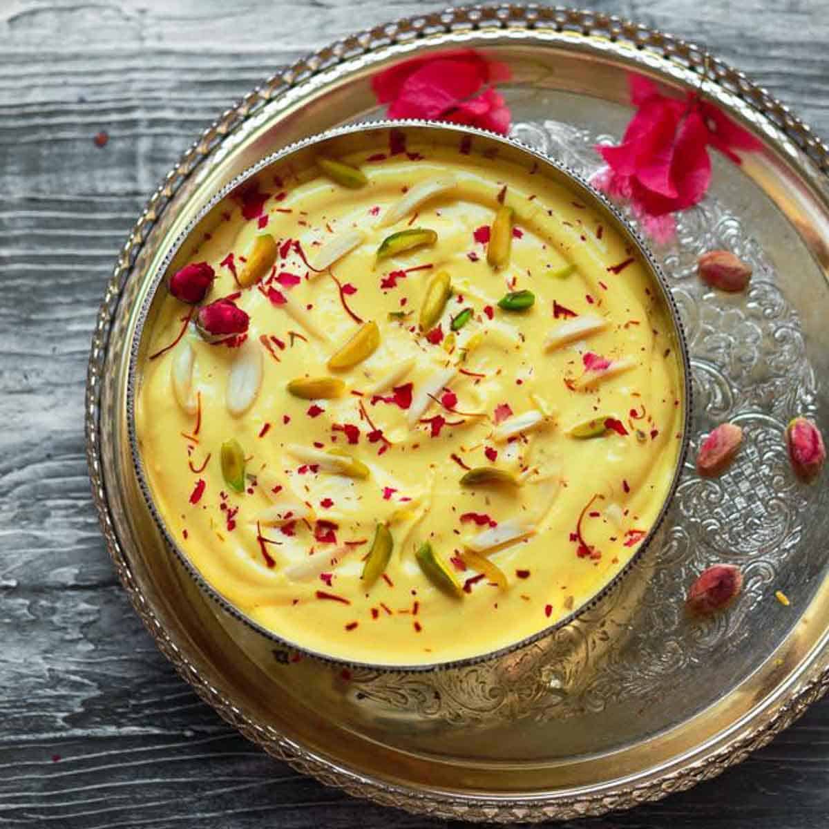 Mango shrikhand in a silver bowl on a silver tray.