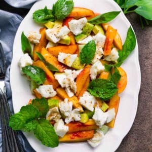 Peach salad with mozzarella on a white platter.