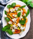 Peach salad with mozzarella on a white platter.
