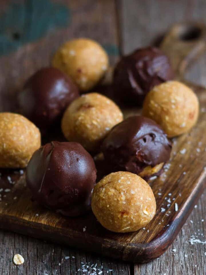 Plain and chocolate coated protein balls on a wooden board.