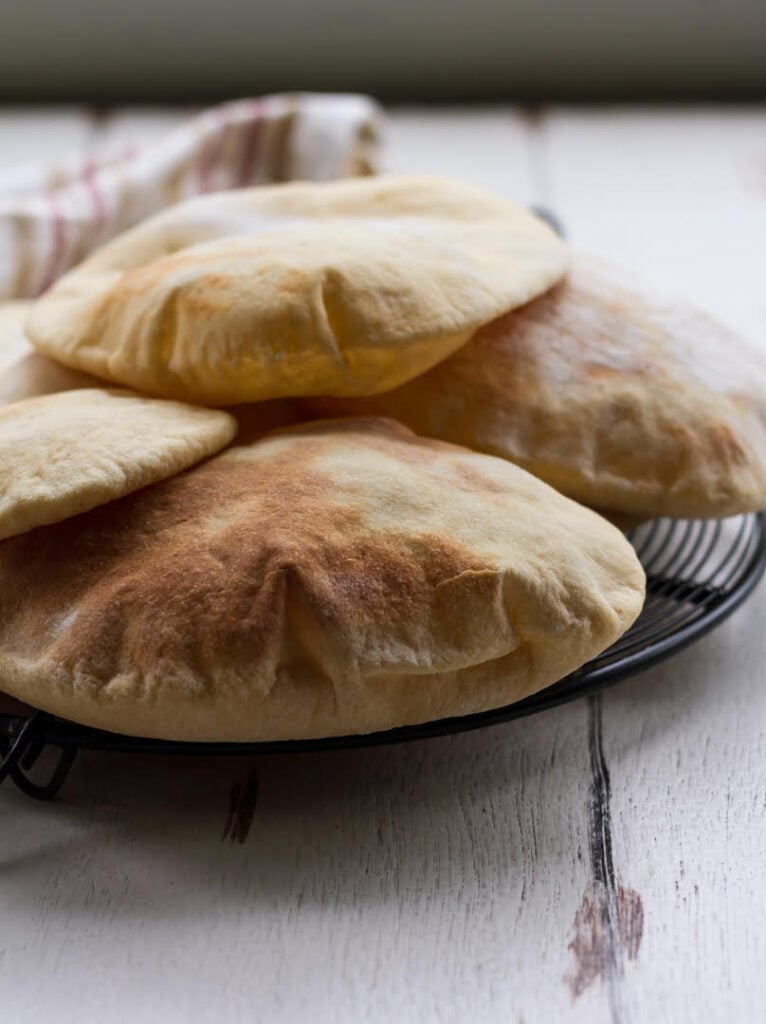 puffed up pita breads on a black metal trivet.