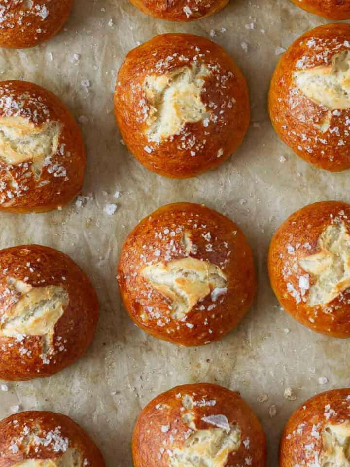 Homemade pretzel buns on parchment paper.