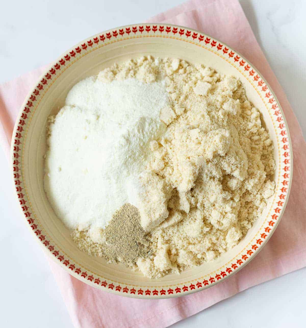 Ground cashews, cardamom powder, and milk powder in a bowl.