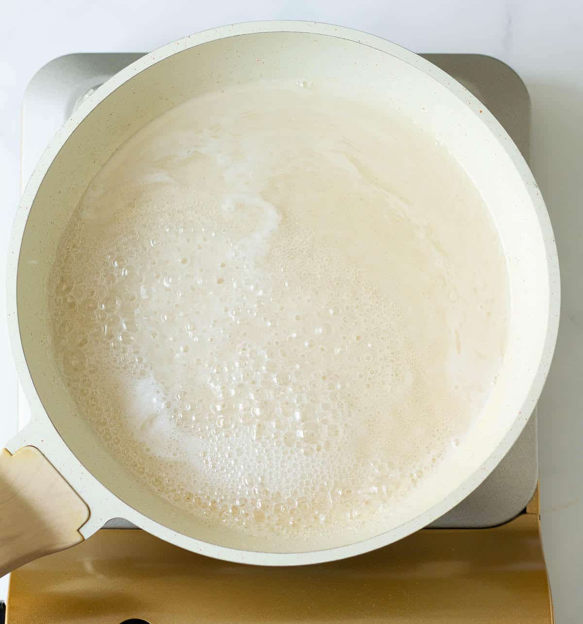 A saucepan with boiling sugar and water mixture.