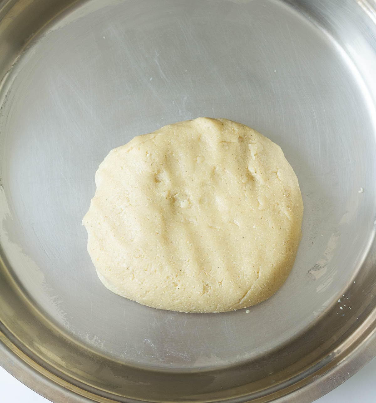 Cashew burfi dough in a stainless steel plate.