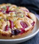 A cake with plums and apricots on a plate.