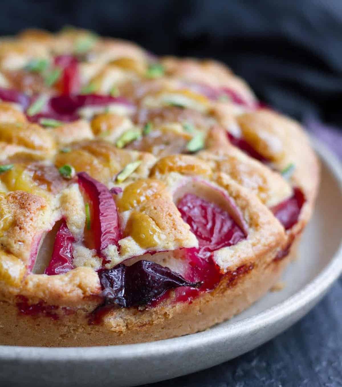 A cake with plums and apricots on a plate.
