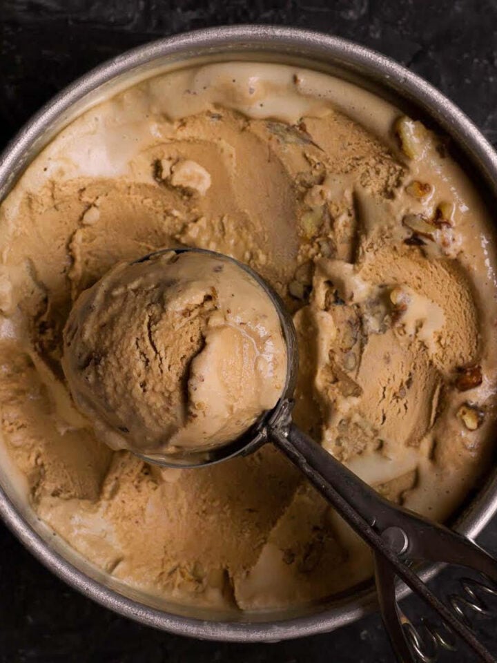 Coffee ice cream in a pan with one scoop in an ice cream scoop.