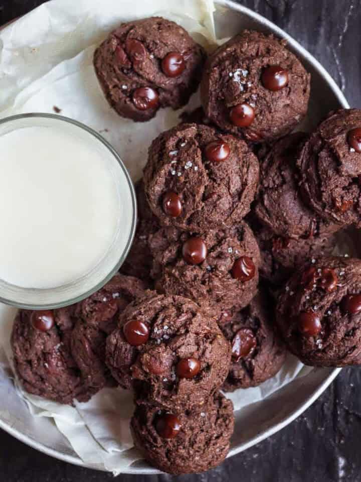 A plate of chocolate cookies with a glass of milk.