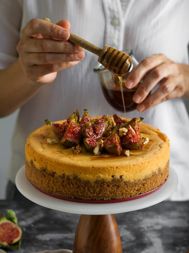 Pouring honey on Cinnamon Cheesecake Recipe | cinnamon cheesecake with roasted figs, honey and walnuts