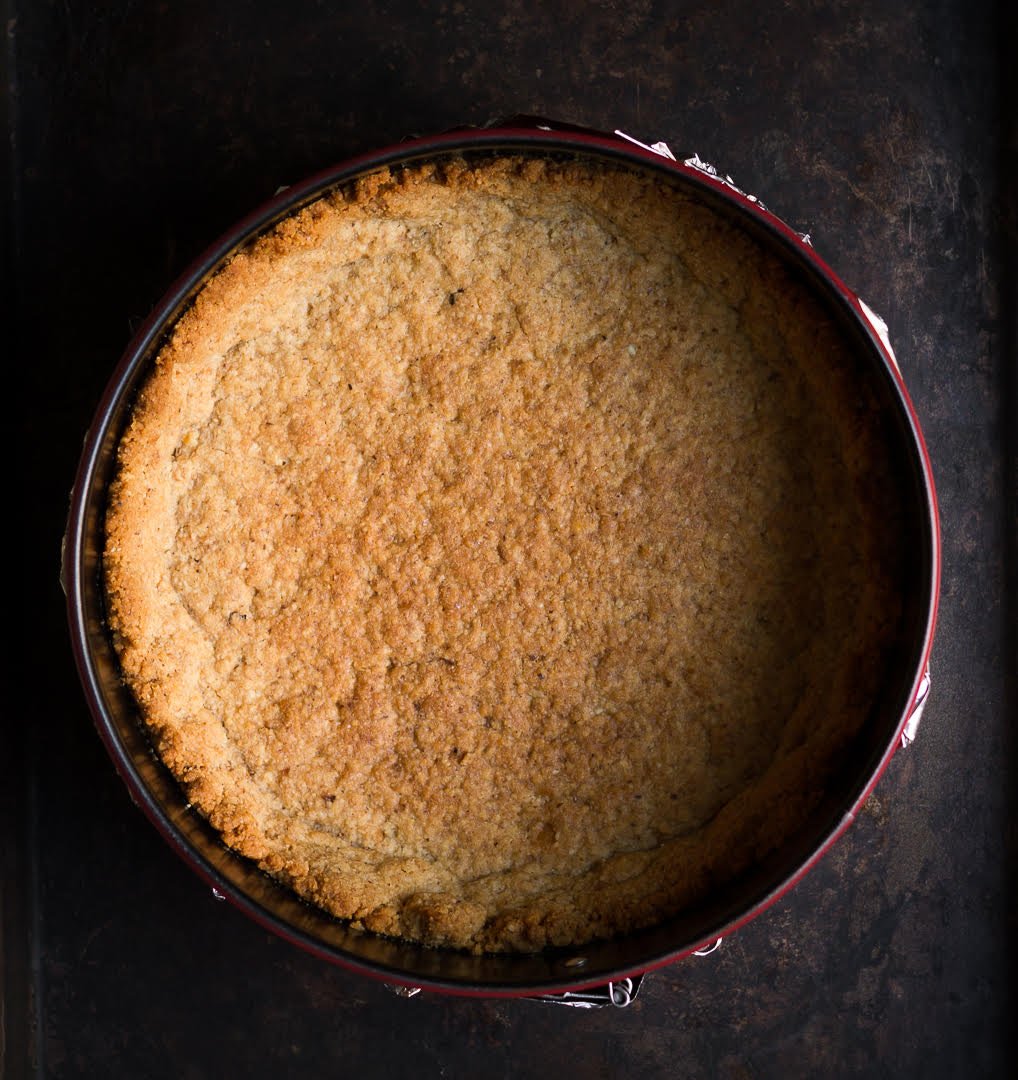 Baked crust for cheesecake in a cake pan.
