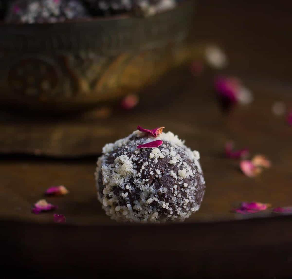 A chocolate peda rolled in almond meal on a plate.